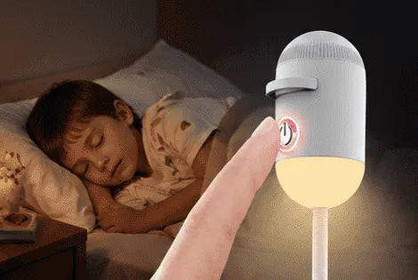 A finger taps the lamp once and it glows warm beside a sleeping boy